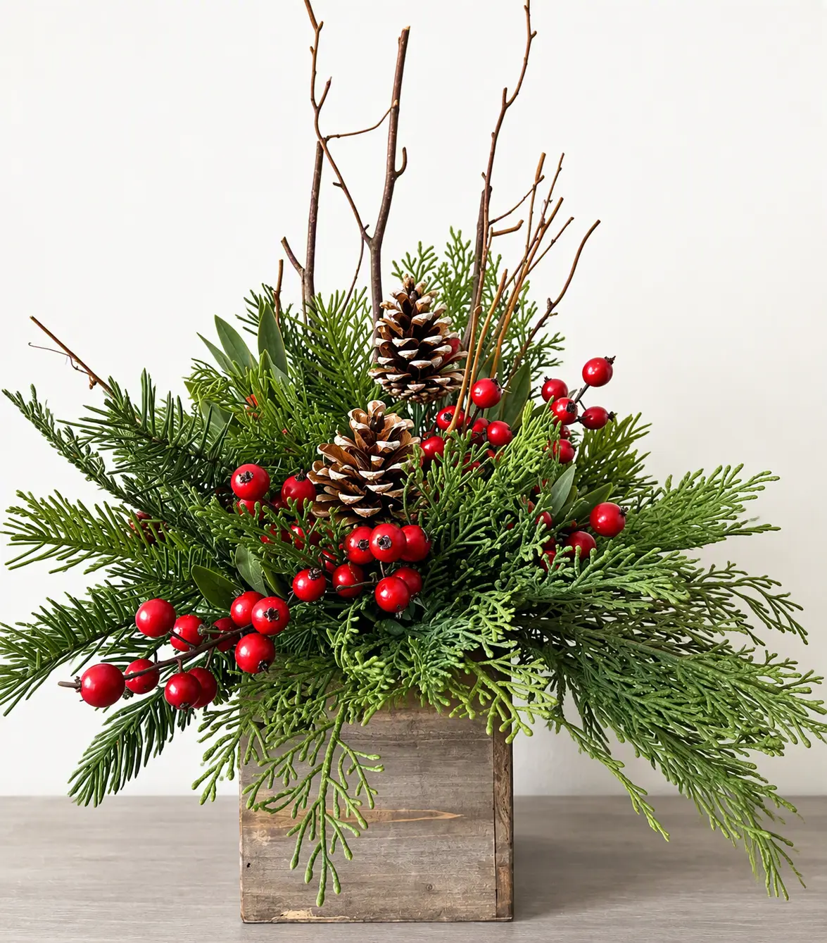 Rustic wooden box centerpiece with evergreen, pinecones, red berries and branches